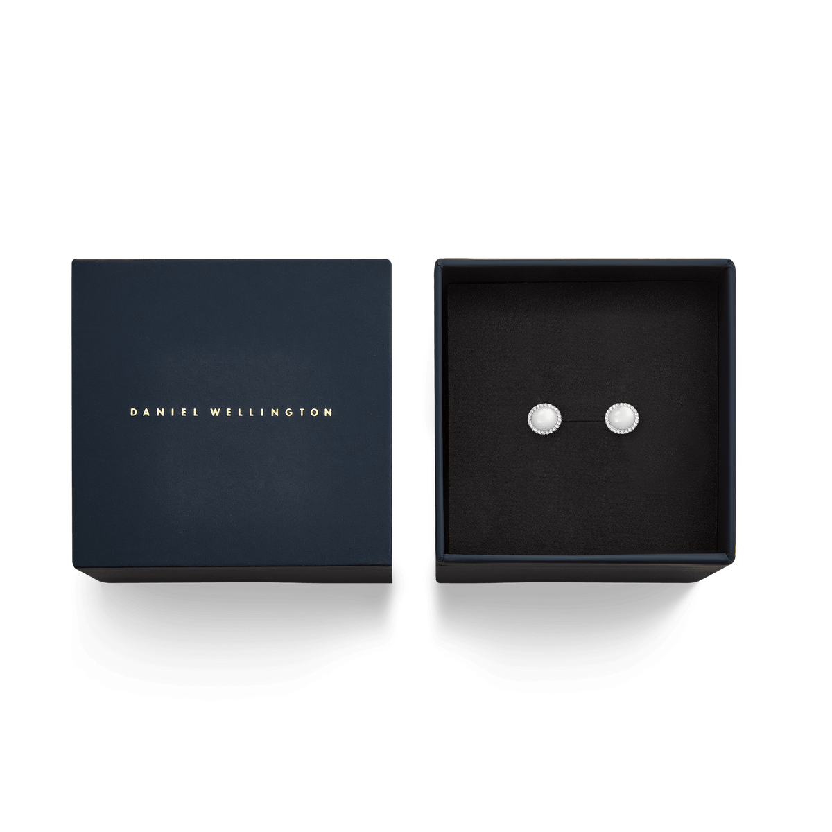 The silver Audrey stud earrings with mother-of-pearl and crystal accents are elegantly placed in a black jewellery box next to the dark blue Daniel Wellington gift box.
