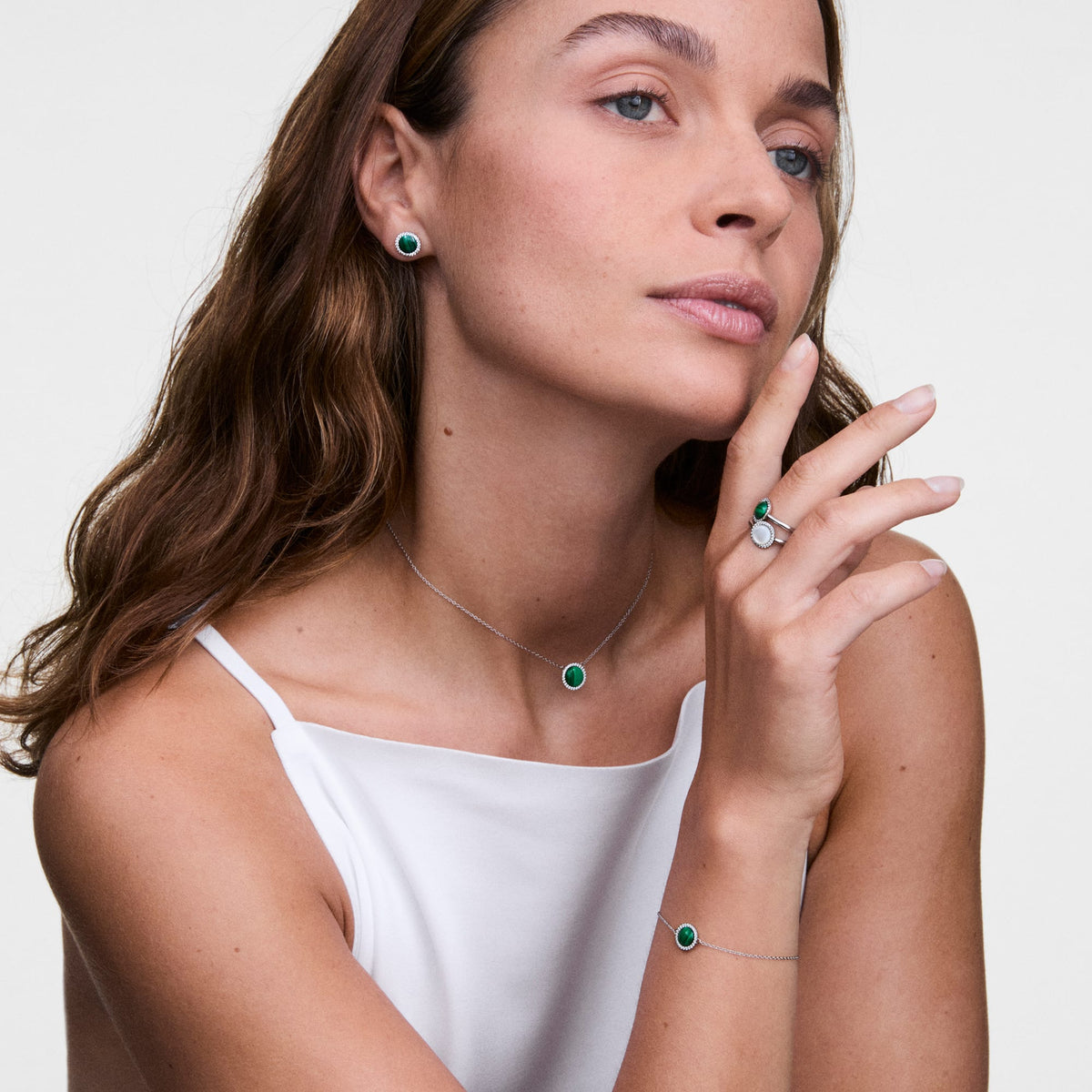 Woman wearing the Audrey Ring Jade Silver with green jade stone and zirconia crystals on her finger, combined with a matching necklace, bracelet and earrings from the same collection.