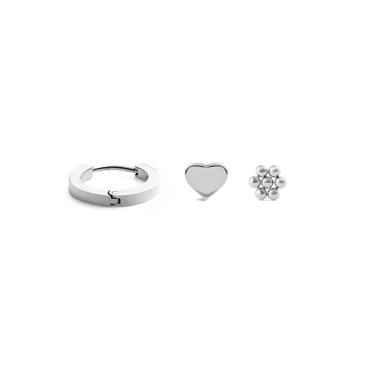 Set de tres pendientes de plata en acero inoxidable con diseños de aro, corazón y flor sobre fondo blanco