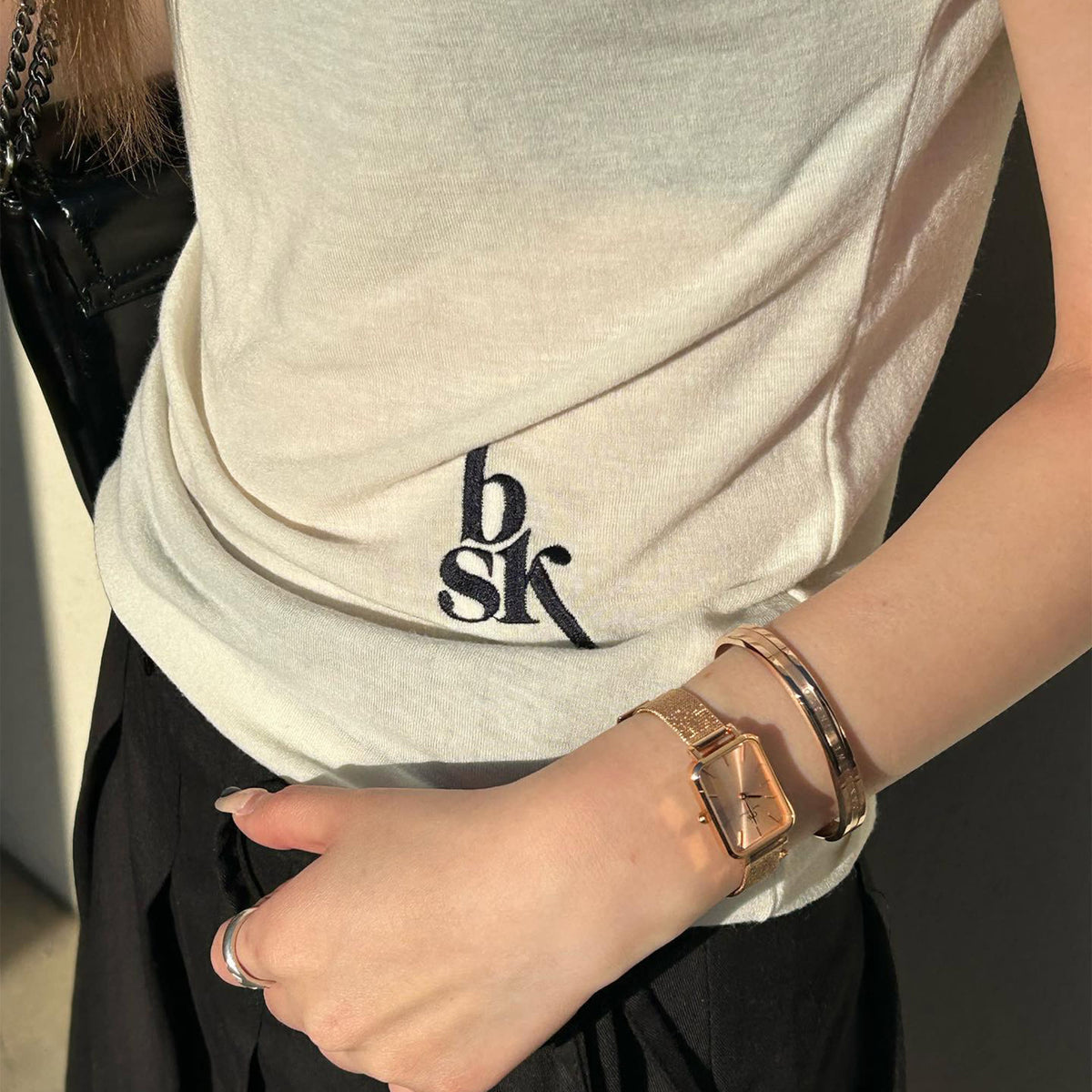 The Quadro Pressed Unitone women's watch in rose gold with a rectangular dial and fine mesh strap is worn on the wrist and stylishly paired with a matching bangle.
