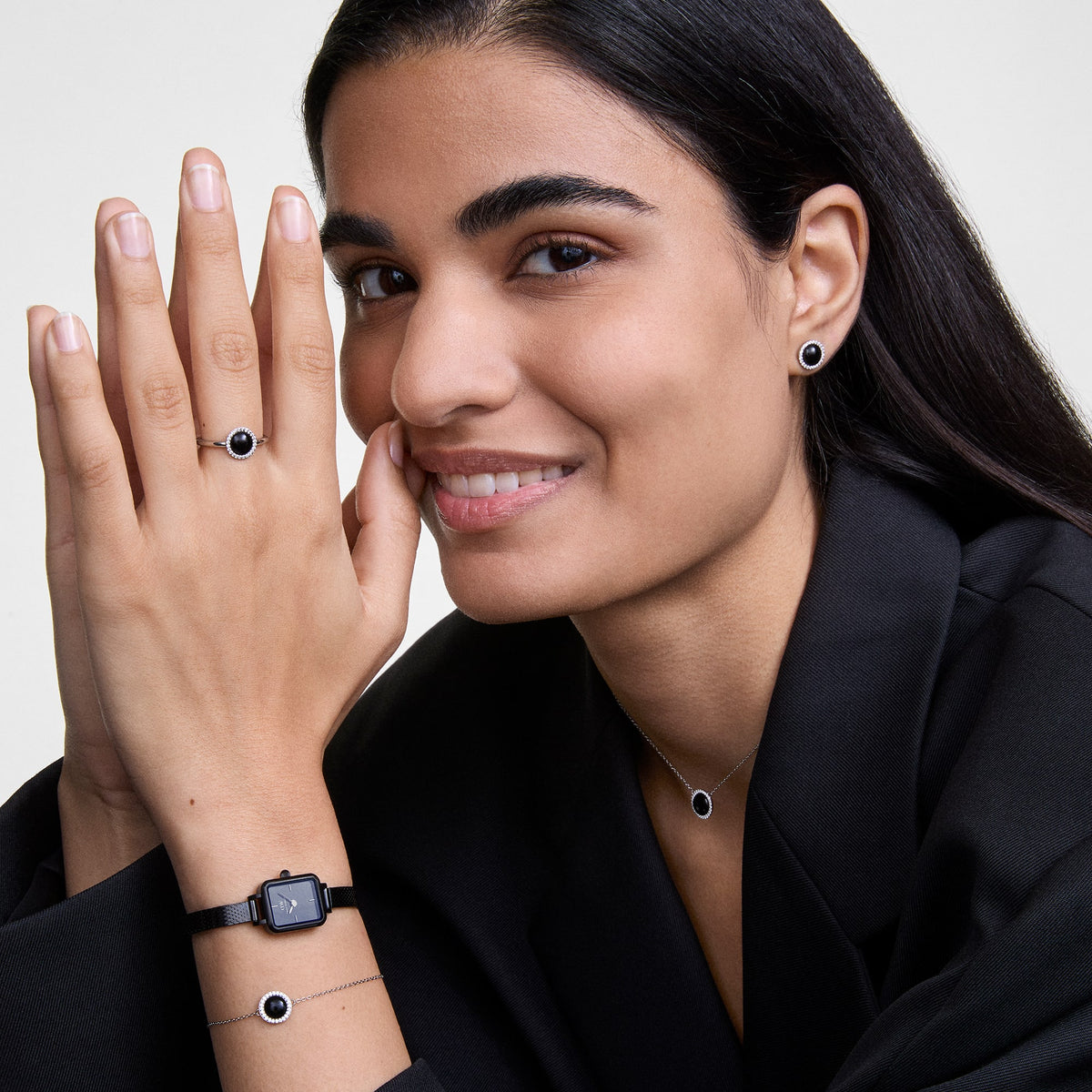 A woman wears the Audrey Bracelet Black Agate Silver on her wrist, paired with a matching ring, earrings and necklace featuring black agate and zirconia, creating an elegant and coordinated look.