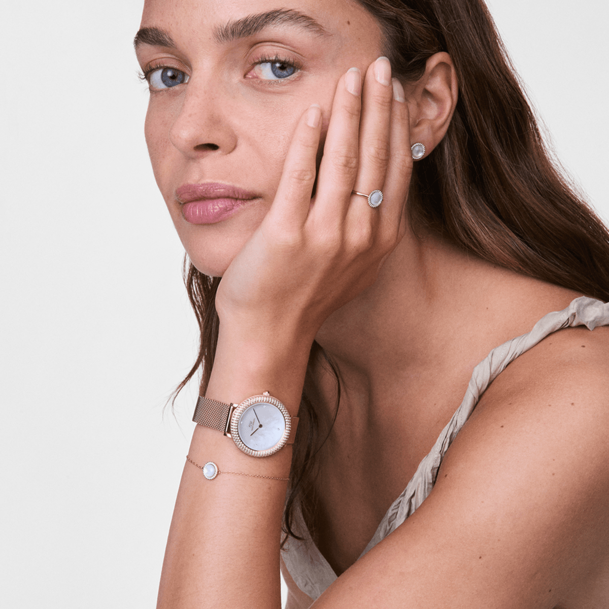Woman wearing the Crystalline Bezel & Audrey MOP Rose Gold Set with a rose gold ladies' watch, shimmering mother-of-pearl dial, delicate bracelet and matching ring, creating an elegant and modern look on the wrist and hand.