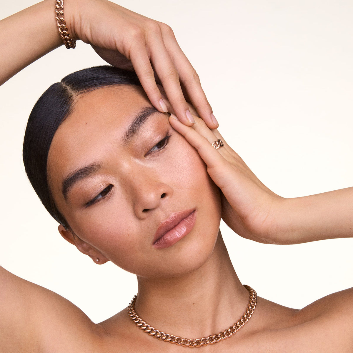 Modelo luciendo la pulsera Chunky Chain Bracelet Rose Gold en la muñeca junto con un collar y un anillo a juego en oro rosa, mostrando el conjunto de joyas con acabado pulido.