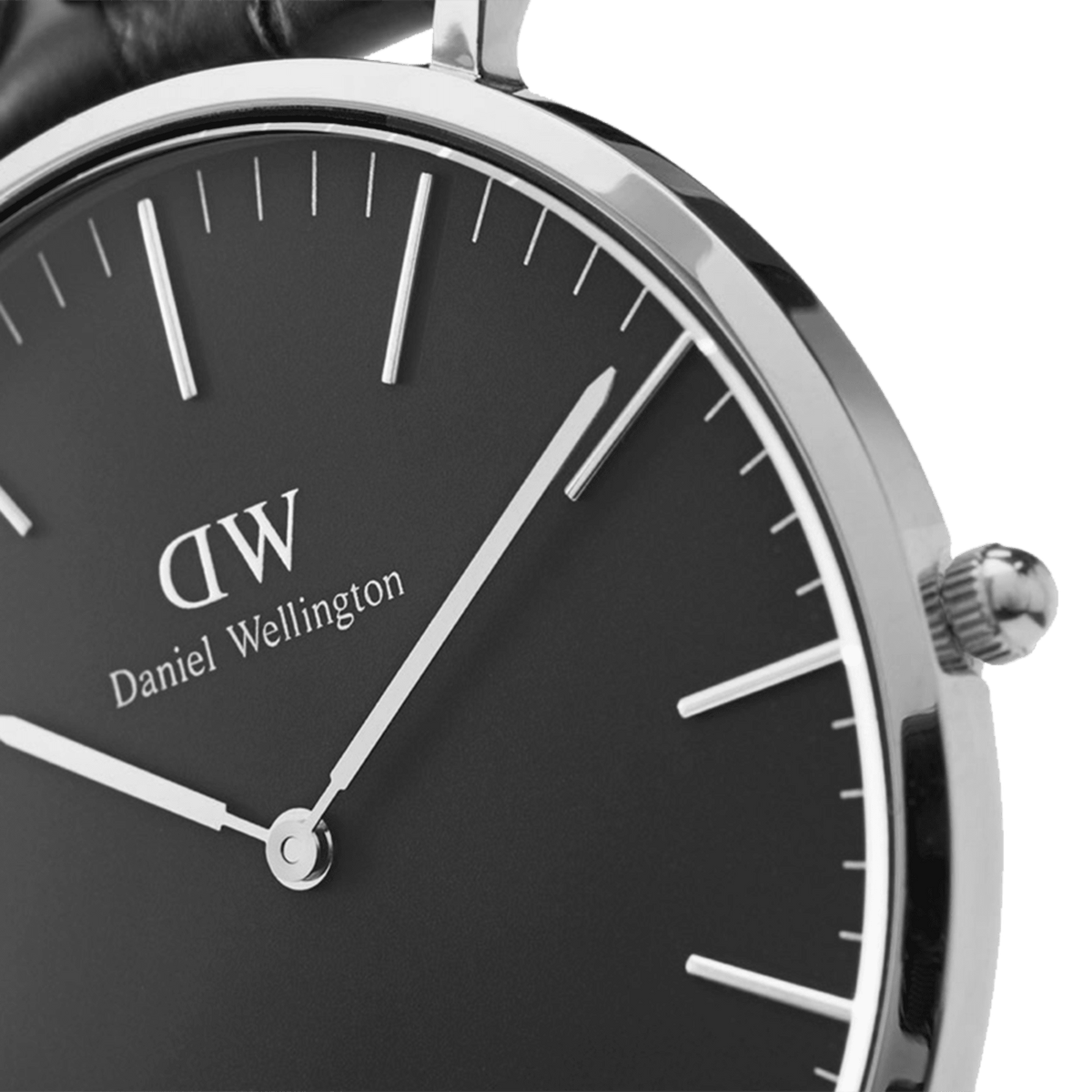 Dettaglio ravvicinato del quadrante nero con indici lineari argentati e logo Daniel Wellington. Cassa in acciaio lucido e corona zigrinata ben visibile.