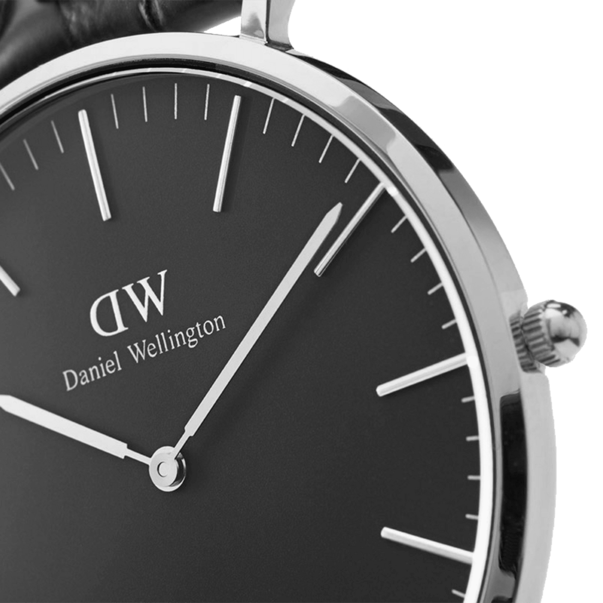 Dettaglio del quadrante nero con logo Daniel Wellington, lancette argentate affusolate e cassa sottile in acciaio lucidato a specchio, completata da una corona zigrinata.