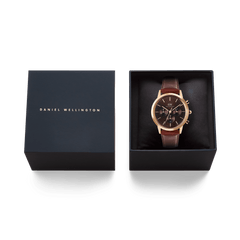 El reloj Iconic Chronograph St Mawes Amber RG presentado en su caja de regalo Daniel Wellington de color azul oscuro con interior acolchado negro.