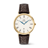 Orologio con numeri romani e datario, caratterizzato da una cassa dorata da 40 mm. Il quadrante bianco presenta numeri romani neri e lancette blu, abbinato a un cinturino in pelle marrone scuro con texture *Croc Belly*.