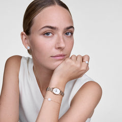 Woman wearing the Audrey ring in rose gold with mother-of-pearl and zirconia, combined with a matching bracelet, earrings, and an elegant watch for a harmonious, modern look.