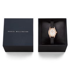 Confezione regalo Daniel Wellington contenente l'orologio Ophelia Mini, adagiato su un cuscino nero all'interno di una raffinata scatola blu navy con logo dorato.