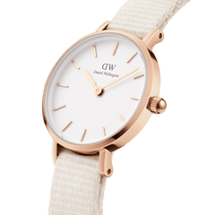 Dettaglio laterale dell'orologio *Petite* con cassa in oro rosa lucido, corona zigrinata e cinturino NATO in tessuto *chalk* con connettori a molla visibili.