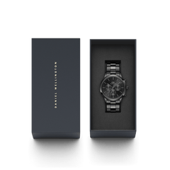 The Iconic Chronograph Link Onyx B lies elegantly in a black Daniel Wellington gift box with gold lettering.