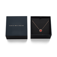 Audrey necklace in rose gold with red agate pendant and zirconia crystals, elegantly presented in a black Daniel Wellington gift box.