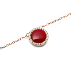 Close-up view of the round pendant of the Audrey necklace in rose gold with red agate and surrounding white zirconia crystals.