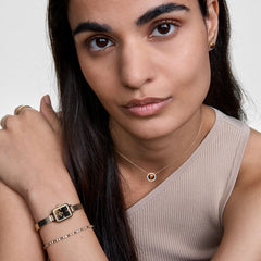 A woman wears the elegant Quadro Mini Reflection Gold ladies' watch with a rectangular case and gold-coloured mesh strap on her wrist, paired with subtle jewellery for a stylish, modern look.